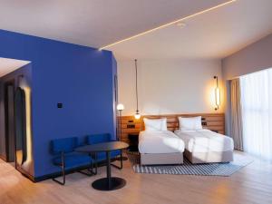 a bedroom with two beds and a table and a blue wall at Novotel Madinah in Medina