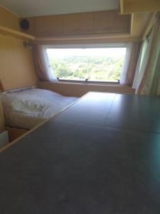 a small bedroom with a bed and a window at La caravane de l'enchanteresse in Philippeville