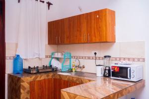 a kitchen with wooden cabinets and a microwave on a counter at MERED Haven Studio in Kilifi