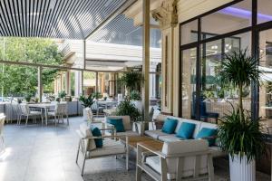 a restaurant with white chairs and tables and windows at Ramada by Wyndham Shymkent in Shymkent