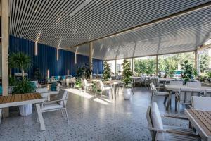 a dining room with tables and chairs and windows at Ramada by Wyndham Shymkent in Shymkent