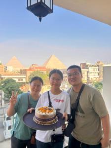 a group of three men holding a cake on a table at The Platinum Pyramid view inn in Cairo