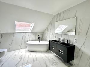 a white bathroom with a tub and a sink at Modern Country House in Merzig