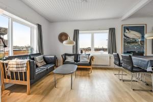 a living room with a black leather couch and chairs at Activity House With Wellness Area-Sj700 in Thyborøn