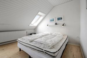 a white bedroom with a bed in a attic at Activity House With Wellness Area-Sj700 in Thyborøn