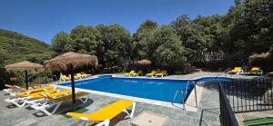 a swimming pool with chairs and umbrellas at Casas Rurales Cortijos el Encinar in Torres