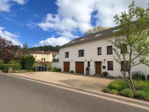 a white house with brown doors on a street at Modern Country House in Merzig