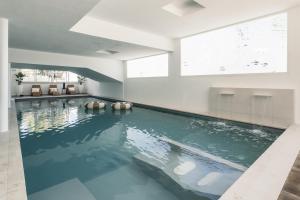 an indoor swimming pool with blue water in a building at Hotel Continental in Senigallia