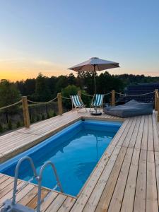 a swimming pool on a wooden deck with an umbrella at Slow Home in Dziemiany