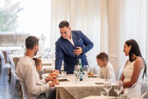 a man in a suit standing at a table in a restaurant at Hotel Continental in Senigallia