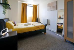 a bedroom with a bed with yellow sheets and a mirror at Stylish 2-Bed Apartment, Free Parking, Walk to Hospital & Uni in Sheffield