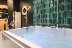 a bath tub with water in a room with wine glasses at SPA Balnéo des Sacres-REIMS-Centre Ville in Reims