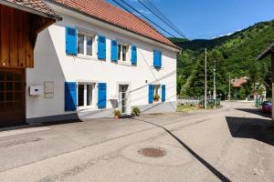 a building with blue shutters on a street at Gite Les Jonquilles in Mittlach
