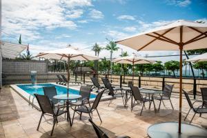 a patio with tables and umbrellas and a pool at Praia Hotel Enseada in Maceió