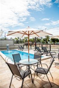 a table and chairs with an umbrella next to a pool at Praia Hotel Enseada in Maceió
