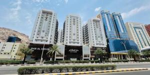 a street in front of tall white buildings at شقه دار المشاعر فى دار الاركان لشقق لاكجرى in Mecca