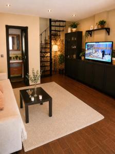 a living room with a couch and a flat screen tv at Dúplex con Piscina y Terraza a 5 min de Sevilla in Camas
