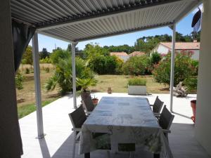 a patio with a table and chairs under a pergola at Océane in Saint-Augustin