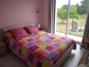 a bedroom with a bed with a colorful quilt and a window at Océane in Saint-Augustin