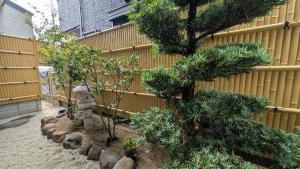 a garden with trees and rocks next to a fence at Dream Stays SORA in Izumi-Sano