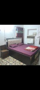 a bedroom with a bed with purple sheets and a drawer at Sakshi Gopal in Vrindāvan