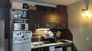 a kitchen with wooden cabinets and a white refrigerator at Casa do Farol - апартамент с басейн до плажа на къмпинг "Градина" in Chernomorets