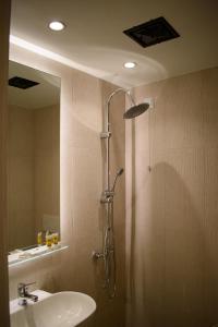 a bathroom with a shower with a sink and a mirror at Hotel ALS KARYSTOS in Karistos