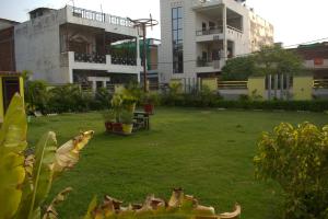 a green yard with buildings in the background at Hotel Harsh Garden in Varanasi