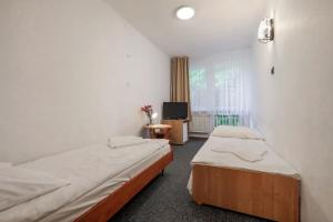 ein Hotelzimmer mit zwei Betten und einem Fernseher in der Unterkunft Ośrodek Wypoczynkowy Eden Kąty Rybackie in Kąty Rybackie + 30 Fotos