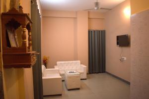 a living room with a white chair and a couch at Hotel Harsh Garden in Varanasi