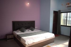 a bedroom with a bed in a room with purple walls at Hotel Harsh Garden in Varanasi