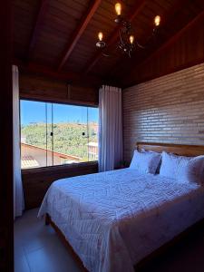a bedroom with a bed and a large window at Chalé Pazinato in Venda Nova do Imigrante
