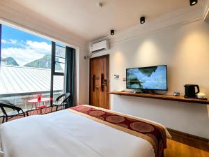 a bedroom with a bed and a tv on a wall at 芮嘉民宿 阳朔西街店 in Yangshuo