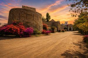 a dirt road with flowers on the side of a building at Castle Bijaipur - A Luxury Heritage Resort, Chittorgarh in Bijaipur