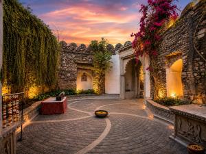 an empty courtyard with a stone building with a sunset at Castle Bijaipur - A Luxury Heritage Resort, Chittorgarh in Bijaipur
