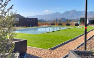 a swimming pool with green grass in front of a building at Chalet Kudu in Ladismith