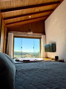 a bedroom with a large window with a large bed at Chalé Pazinato in Venda Nova do Imigrante