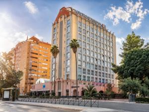 a tall building with palm trees in front of it at Vértice Sevilla in Seville