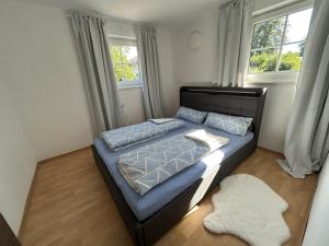 a bedroom with a blue bed with two windows at Landhaus Heck in Pfronten