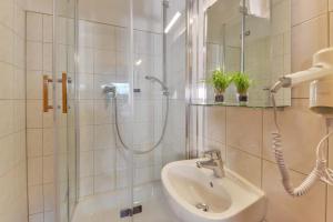 baño blanco con ducha y lavamanos en My Hostel, en Múnich