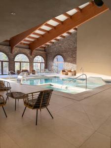 a pool in a building with chairs and a table at Hotel & SPA Llop Gris in El Tarter