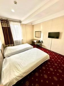 a hotel room with two beds and a desk at Harmony Inn in Almaty
