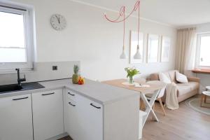 a kitchen with white cabinets and a table and a couch at Meerblick D9 mit Balkon und Pool in Wangerland