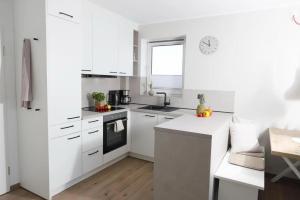 a white kitchen with white cabinets and a sink at Meerblick D9 mit Balkon und Pool in Wangerland