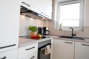a kitchen with white cabinets and a sink with fruits and vegetables at Meerblick D9 mit Balkon und Pool in Wangerland