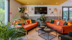 a living room with orange couches and plants at Campanile NATURE - Orange in Orange