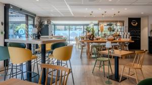 a restaurant with tables and chairs in a cafeteria at Campanile NATURE - Orange in Orange