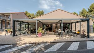 a patio with tables and chairs in front of a building at Campanile NATURE - Orange in Orange