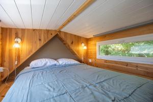 a bedroom with a bed in a room with a window at Tiny House au coeur de la nature in Bessuéjouls