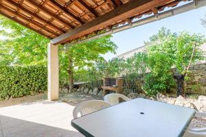 a patio with a table and chairs under a pergola at Le Cade - La Fontinelle in Bessas